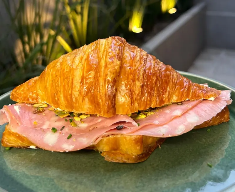 Croissant relleno de jamón y queso sobre un plato verde