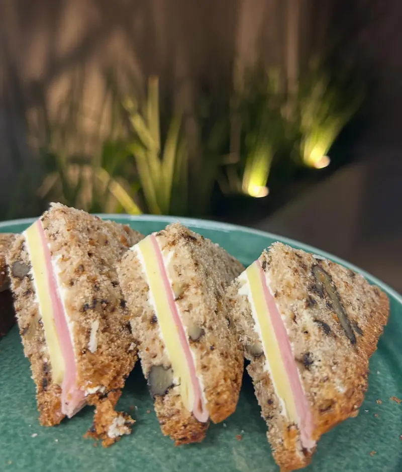 Tres sandwichitos de pan de nuez con jamón y queso, en plato verde