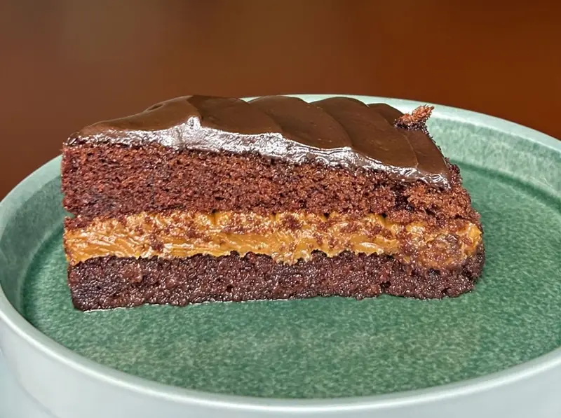 Porción de torta de chocolate con dulce de leche en plato verde